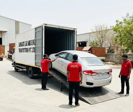 Car with RJ number plate being loaded into closed container carrier by professional transport team