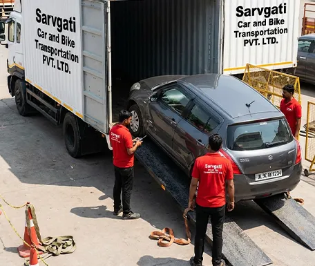Car with Delhi number plate being loaded into a closed container truck by Sarvgati Car and Bike Transportation PVT. LTD. team in red uniform
